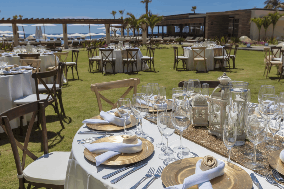 Elegant garden wedding banquet at Krystal Grand Los Cabos with gold table setting and oceanfront event space.